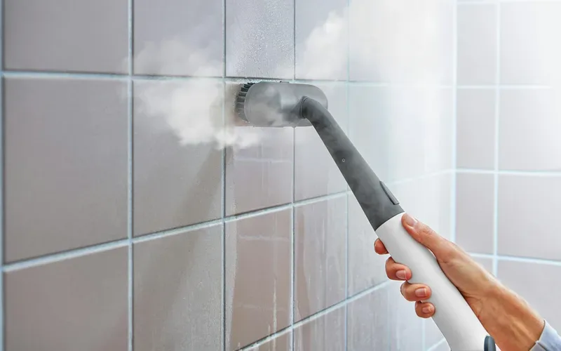 Steam cleaner lifting grime from tiled bathroom walls